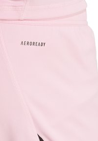 Helle rosa Sportshorts aus glattem Material mit einem AEROREADY-Logo, kontrastierenden schwarzen Akzenten und sichtbaren Nähdetails.