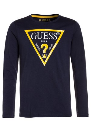 Chemise à manches longues bleu marine avec un grand logo triangulaire jaune indiquant "GUESS U.S.A." et un point d'interrogation au centre.