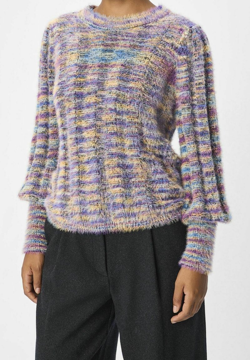 Pull tricoté duveteux multicolore avec des rayures pastel, porté avec un pantalon noir ample, vu des épaules aux hanches.