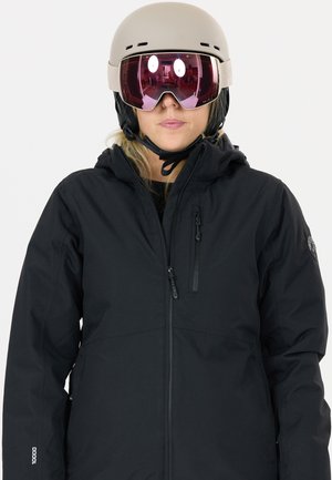 Musta vedenpitävä hiihtotakki, jossa on vetoketjullinen etuosa, säädettävä hupullinen ja vetoketjulliset taskut. Päällä beige kypärä ja vaaleanpunaiset linssit omaavat suojalasit.