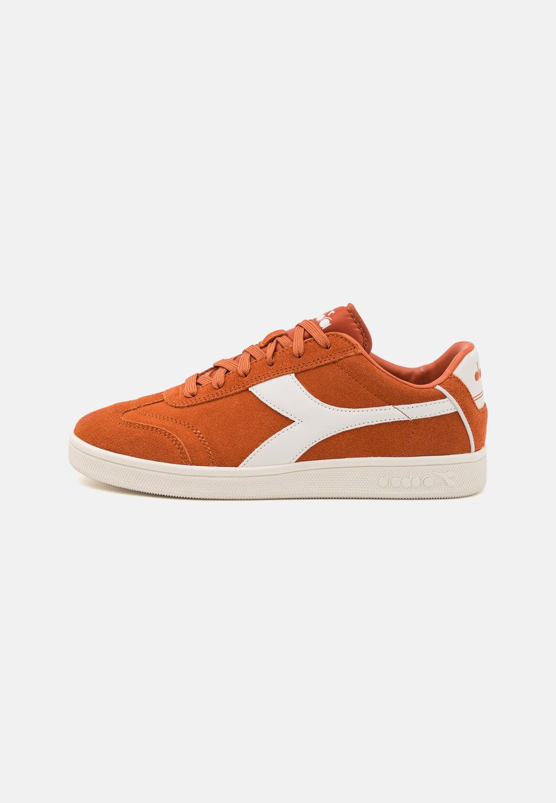 Oransje semsket sneakers med hvite detaljer, teksturert overdel, rund tå og gummisåle. Har snøring og merke på tungen og hælen.