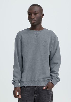 Grå sweatshirt med lange ærmer, ribstrikkede manchetter og kant, med en trekantet halsudskæring og subtil rund logobroderi på brystet.