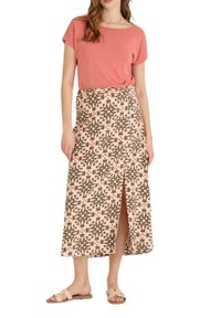 Top de manga corta color rosa claro combinado con una falda maxi estampada que presenta diseños florales en verde y rosa. La falda tiene una abertura frontal. Sandalias planas.