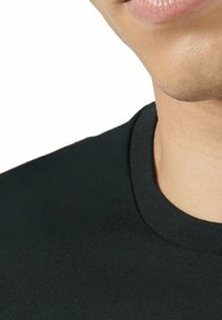 Częściowy widok dolnej części twarzy i szyi osoby w czarnej koszulce z okrągłym dekoltem na białym tle.