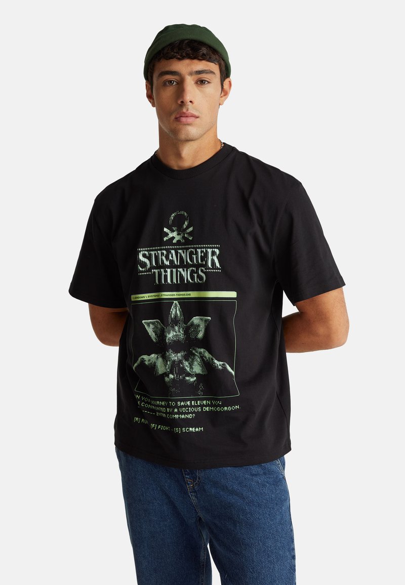 Černé bavlněné tričko s grafickým potiskem Demogorgona s zelenými akcenty a textem souvisejícím s "Stranger Things." Volný střih.