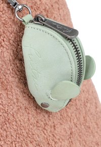 Petit porte-monnaie vert menthe en forme de souris avec des oreilles, fermeture éclair en métal et clip attaché à un tissu rose texturé.