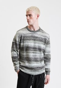 Gestrickter Pullover mit mehrfarbigen horizontalen Streifen in Grau, Schwarz und Weiß. Verfügt über einen runden Halsausschnitt sowie gerippte Bündchen und Saum.