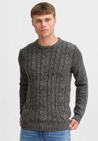 Gray knitted sweater with a textured cable pattern, crew neckline, and ribbed cuffs and hem. Features a small brown brand patch on the side.