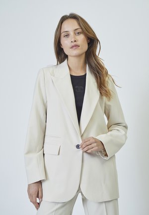 Beige tailored blazer with a notched lapel, single button closure, and front pockets. Smooth texture, structured silhouette, and clean lines.