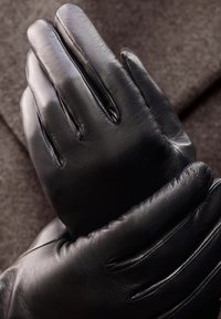 Gants en cuir noir avec une texture lisse, présentant quatre emplacements pour les doigts et des détails de couture. Le matériau semble flexible et doux.