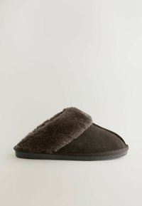 Tmavohnedá nazúvacia papuča s plyšovou umelou kožušinou vo vnútri a vonkajškom z brúseného semišu, so plochou podrážkou, navrhnutá pre vnútorné pohodlie.