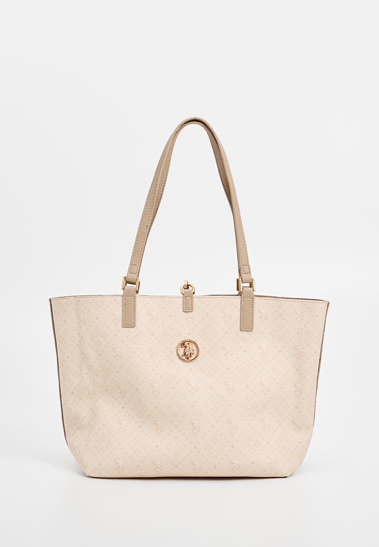 Sac fourre-tout beige en tissu lisse, avec des poignées doubles et une quincaillerie de couleur dorée. Il présente un motif en relief et un emblème central.