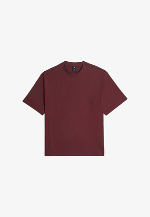 Camiseta de algodón color burdeos con cuello redondo, mangas cortas y un logo sutil en el frente. Textura suave y ajustada clásica.