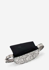 Pequeño bolso cruzado con un exterior de estampado de serpiente blanco y negro, superficie texturizada y un interior de tela negra. Cuenta con un cierre de solapa y una correa ajustable.
