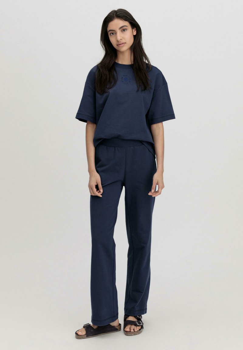 Navyblaues Baumwoll-Outfit bestehend aus einem T-Shirt mit kurzen Ärmeln und einer lockeren Hose. Verfügt über einen runden Ausschnitt und eine lässige Passform.