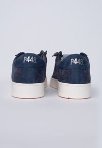 Le sneakers in suede blu navy presentano una suola in gomma bianca. Dettagli notevoli includono un tacco cucito e il marchio "P448" sul retro.