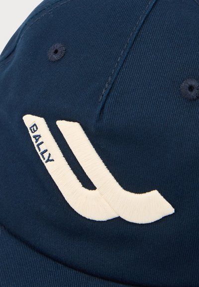 Σκούφος από ύφασμα σε ναυτικό μπλε χρώμα με λευκή κεντημένη επιγραφή "BALLY" και καμπυλωτό διακοσμητικό στοιχείο στην εμπρόσθια επιφάνεια.