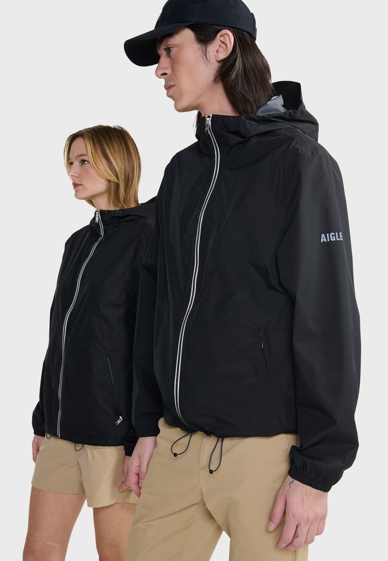 Vestes légères noires avec capuches et fermetures éclair avant, dotées d'un cordon de serrage à l'ourlet et d'un logo brodé sur la manche.