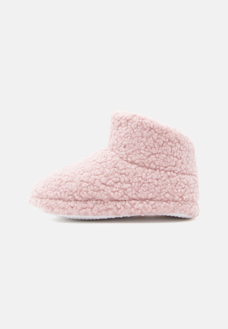 Chausson en polaire rose avec une surface douce et texturée, un bout arrondi et une conception à cheville basse. Il est doté d'une semelle en caoutchouc blanc pour une meilleure adhérence.