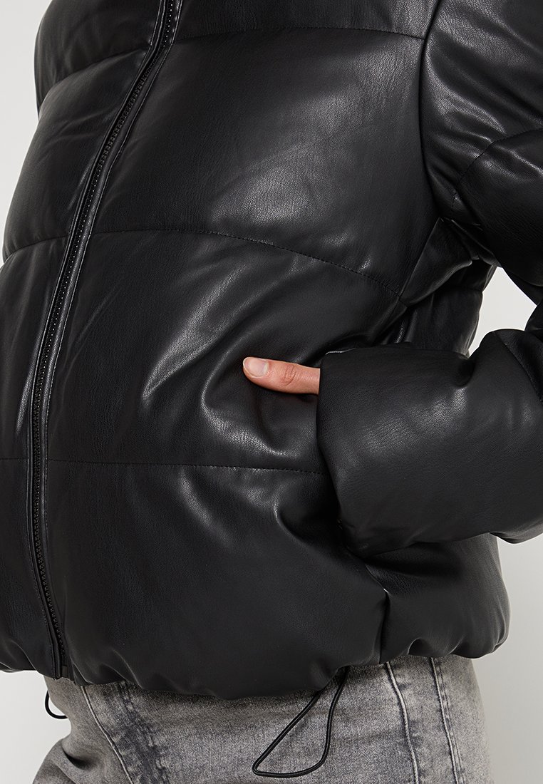 Giacca a vento nera con finitura in pelle lucida, dotata di chiusura con zip e tasche laterali. Il design include sezioni imbottite e orlo con coulisse.