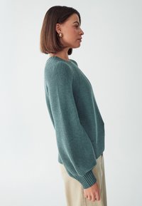 Gestrickter Pullover in Teal mit rundem Ausschnitt, gerippten Bündchen und lockerer Passform. Verfügt über einen strukturierten Stoff und leicht puffige Ärmel.