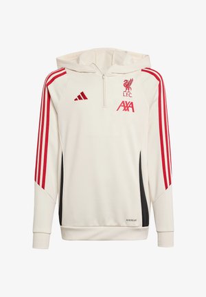 Zwei junge Menschen tragen weiße Liverpool FC-Hoodies mit roten Streifen und schwarze Hosen und stehen vor einem schlichten Hintergrund.