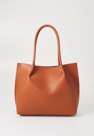 Borsa tote in pelle marrone con due manici lunghi e una finitura liscia, in piedi su uno sfondo chiaro e uniforme.