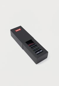 Μαύρη συσκευασία κουτιού με διαφανή τμήμα που εμφανίζει ριγέ κάλτσες σε μαύρο, πράσινο και κόκκινο. Λογότυπο "Levi's" και στο κουτί και στις κάλτσες.