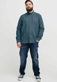 Tume tealdise värvi särgiga, millel on rinna tasku, koos tumesiniste denim pükstega ja musta-valgete triibuliste tossudega. Käsitöö sobivus.
