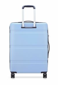 Hard-shell suitcase in light blue, featuring a textured surface, black accents, a telescopic handle, and four swivel wheels for mobility.