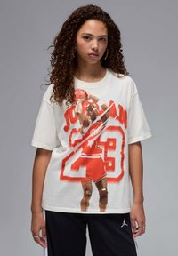 Biała bawełniana koszulka z graficznym nadrukiem koszykarza w czerwono-białych barwach, z wyraźnym napisem "Jordan 23".