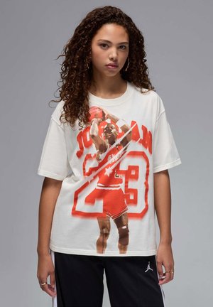 T-shirt en coton blanc présentant un imprimé graphique d'un joueur de basketball en rouge et blanc, avec le texte "Jordan 23" bien en évidence.
