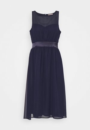 Robe de cocktail bleu marine sans manches avec corsage supérieur transparent, taille cintrée avec ceinture en satin et jupe fluide jusqu'au genou.