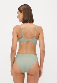 Lichtgroene bikini set met een naadloze, gladde textuur. De beha heeft verstelbare schouderbandjes en een ronde rug, terwijl de slip een hoge uitsnijding heeft.