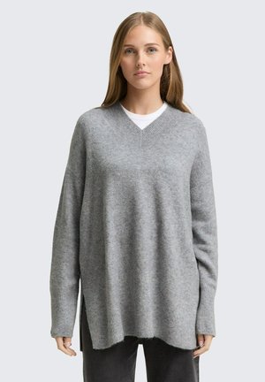 Hellgrauer, oversized Pullover mit V-Ausschnitt, gerippten Bündchen und seitlichen Schlitzen. Weicher Stoff, lockere Passform und lässiges Design.