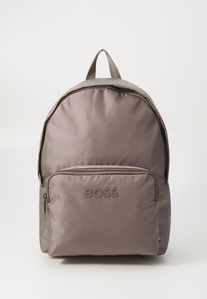 Zaino in nylon grigio con parte superiore arrotondata, dotato di tasca frontale con zip e logo "BOSS" in rilievo. Spallacci regolabili e manico in tessuto.