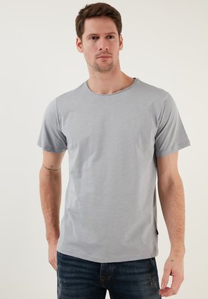 Grå kortærmet t-shirt med rund halsudskæring, glat tekstur, afslappet pasform og detaljer i sidesømmen, båret med mørke jeans.