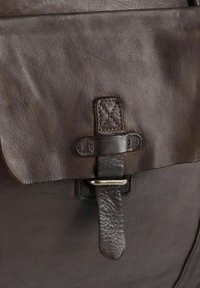 Sac en cuir marron présentant une surface texturée, une fermeture à rabat avec un accent cousu, et un fermoir en métal argenté pour une fermeture sécurisée.
