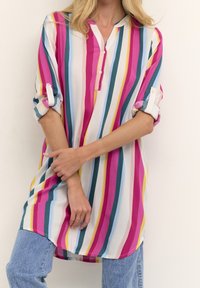 Tunique rayée multicolore avec un col boutonné, comportant des rayures roses, bleu-vert, jaunes et blanches ; tissu léger avec des manches roulées.