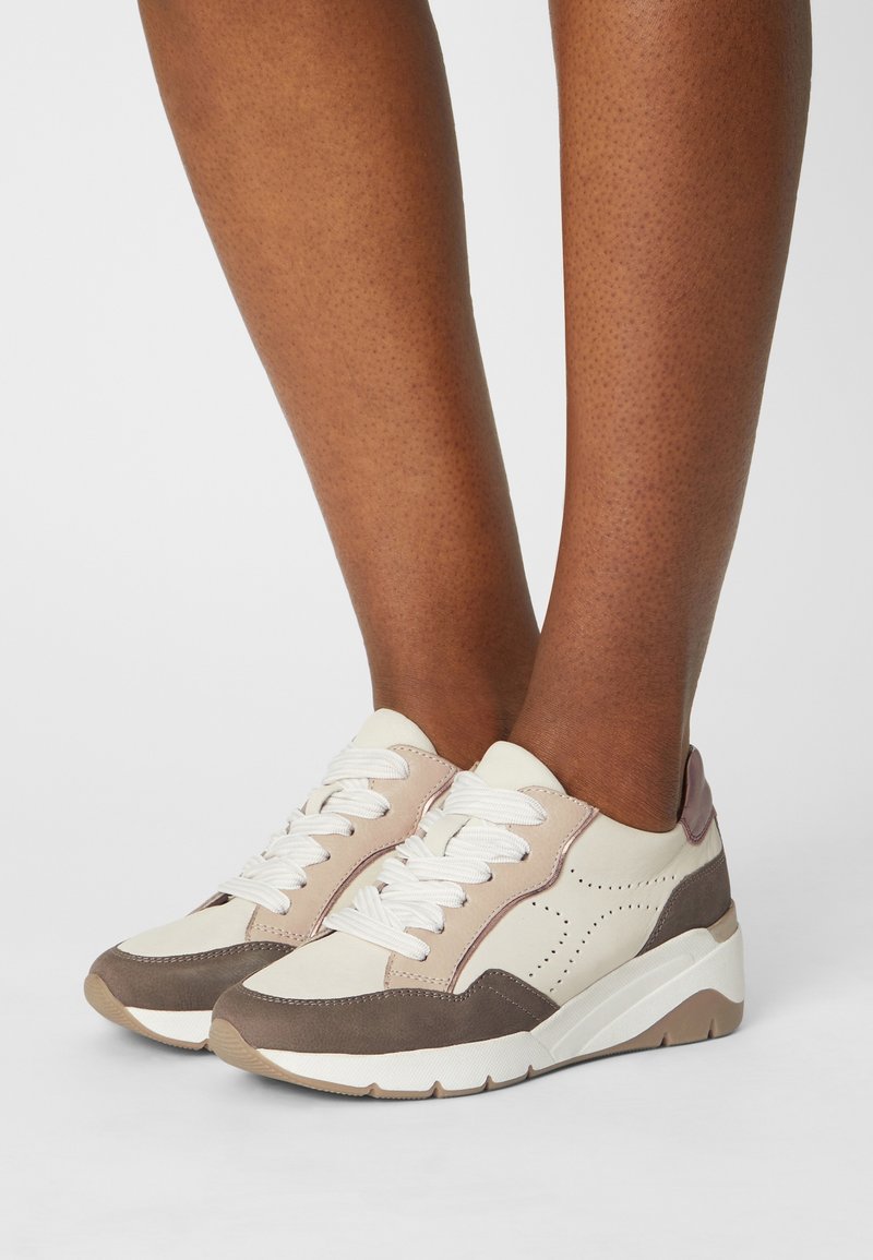 Zapatillas blancas y beige con acentos marrones, de cuero texturizado y tejido, con un diseño perforado, puntera redonda y suela de contraste.