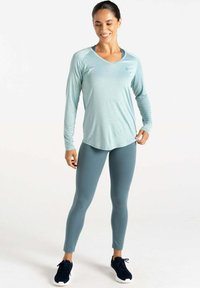 Hellblaues langärmliges Sportoberteil mit V-Ausschnitt, kombiniert mit passenden figurbetonten Leggings. Es zeichnet sich durch ein glattes Material und eine lässige Passform aus.