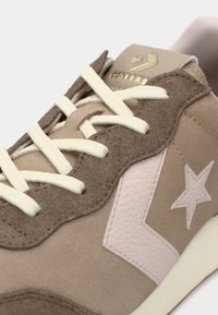 Scarpe da ginnastica in suede marrone e pelle con lacci crema, design a onde, accenti in pelle rosa e logo a stella sul lato.