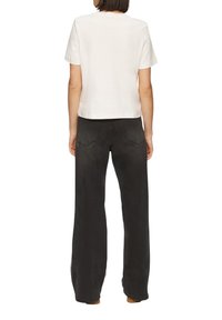 Witte crop top met korte mouwen en een ronde hals. Gecombineerd met zwarte wijde jeans, die een klassieke denimtextuur tonen.