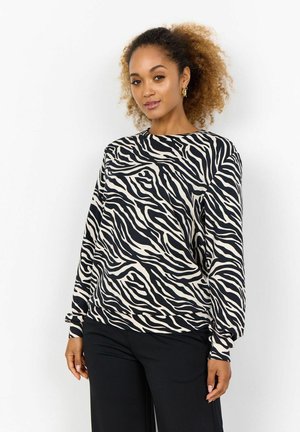 Sweatshirt à imprimé zèbre en crème et noir, avec un col rond, des manches longues et un tissu doux. Assorti avec un pantalon noir.
