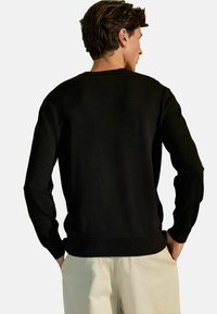Schwarzer Sweatshirt mit langen Ärmeln, rundem Ausschnitt und gerippten Bündchen, aus weichem Stoff, von hinten mit lockerer Passform gezeigt.