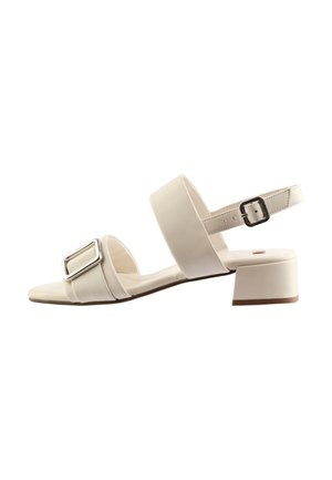 White heeled sandals with a rectangular silver buckle, two wide straps, and a low block heel. Smooth leather-like material and simple design.