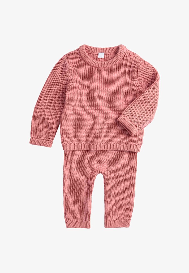 Completo di maglione rosa lavorato a maglia e pantaloni abbinati. Il maglione ha maniche lunghe e collo rotondo, con dettagli di bottoni su una spalla.