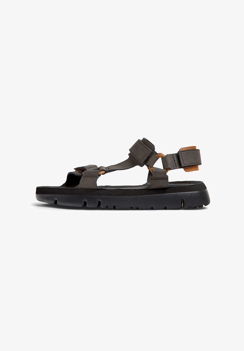 Sandali in pelle marrone con suole in gomma nera. Presentano cinturini regolabili, punta aperta e un design minimalista che offre traspirabilità.