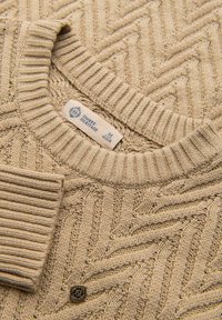 Maglione beige lavorato a maglia con motivo a spina di pesce, collo a costine e bottoniera. Presenta un'etichetta di marca che indica la taglia M.
