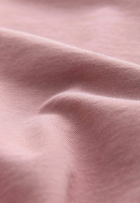 Tissu rose à la texture lisse, présentant des motifs fins et régulièrement tricotés, ainsi qu'un subtil dégradé de lumière. Apparence douce et légère.